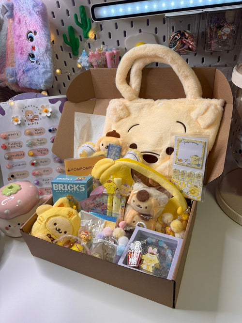 Box filled with various toys and items, including plush bears and small packages, on a white surface.